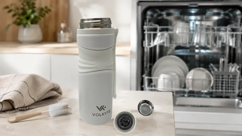Termo VOLKYTE blanco junto a un lavavajillas y accesorios de limpieza